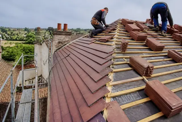 Travailleurs posant des tuiles sur une toiture par aquitainetravauxrenovation.fr couverture toiture