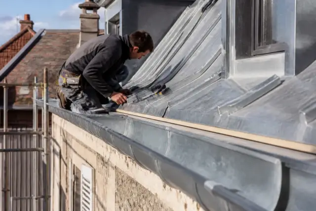 Travailleur effectuant des travaux de zinguerie sur toit pour Aquitaine Travaux Rénovation