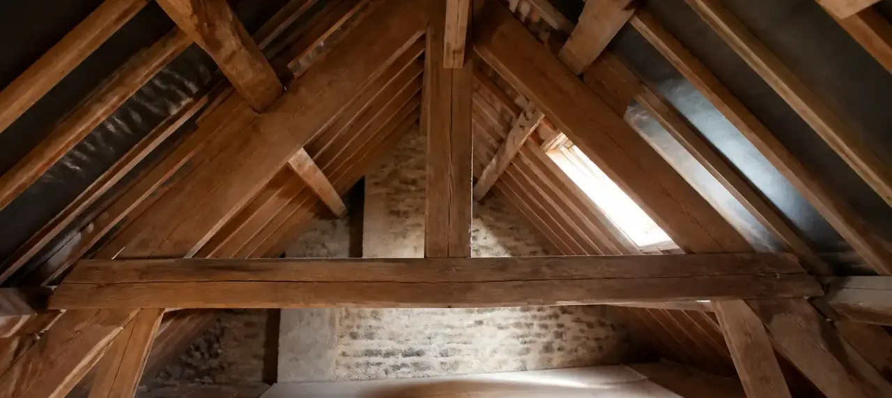 Charpente en bois apparente dans un comble, avec fermes, pannes et chevrons