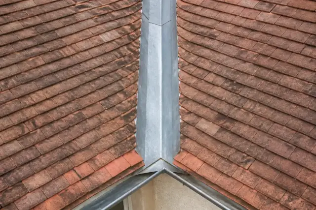 Noue métallique en zinc entre deux versants de toit en tuiles plates, vue d’en haut