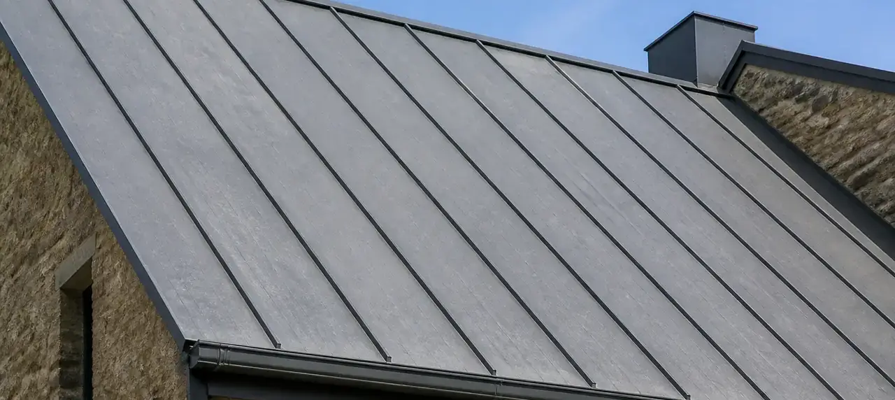 Toit en zinc patiné gris clair posé à joint debout, lignes verticales régulières