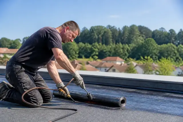 Artisan installant une membrane d'étanchéité sur un toit plat pour couverture Mon Institut du BTP