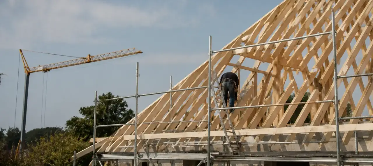 Charpente traditionnelle en cours de levage sur une maison, pièces de bois neuves et échafaudage