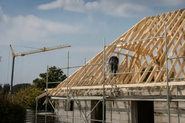 Charpente traditionnelle en cours de levage sur une maison, pièces de bois neuves et échafaudage