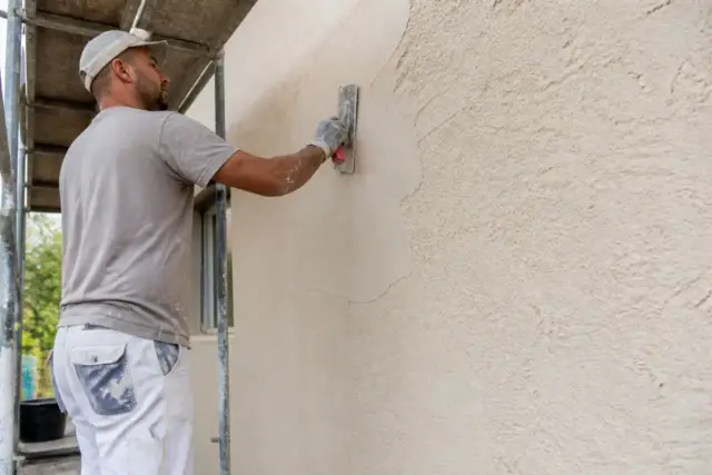 Artisan fixant du crépi mural avec expertise tousrenov.be en extérieur.